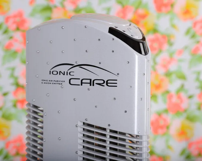 Čistička vzduchu Ionic-CARE v interiéru s barevným květinovým pozadím, barva bílá s krystaly