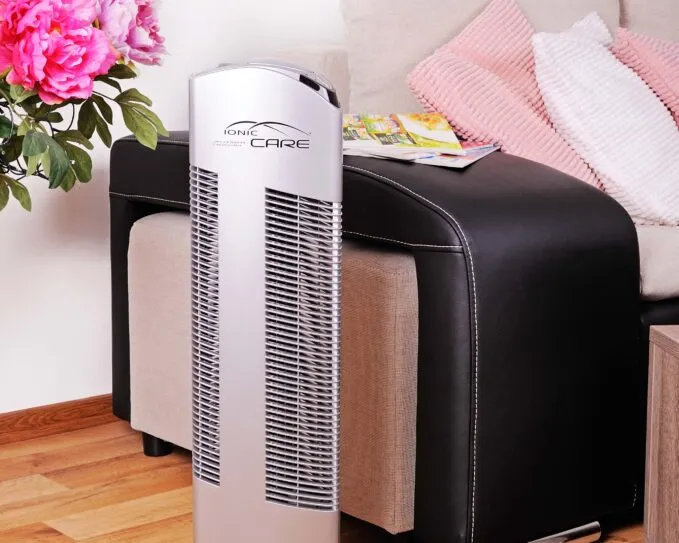 Čistička vzduchu Ionic-CARE před pohovkou a růžovou interiérovou pivoňkou, barva stříbrná