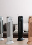 Čističky vzduchu Ionic-CARE ve čtyřech barevných variantách, stříbrná, perleťově bílá, černá a dekor dřeva v pozadí s šedou pohovkou a bílou zdí