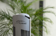 Čistička vzduchu Ionic-CARE v detailu s pokojovou rostlinou v pozadí, barva stříbrná