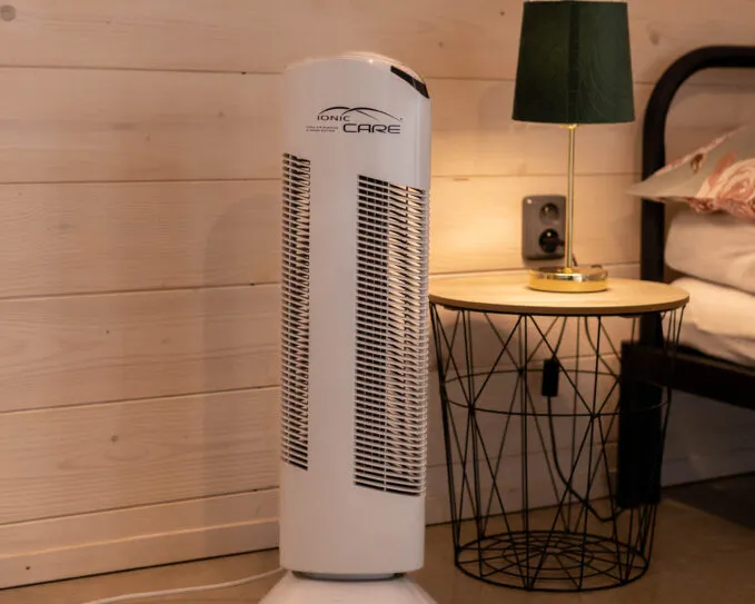 Čistička vzduchu Ionic-CARE v interiéru dřevostavby s postelí a nočním stolkem, barva perleťově bílá