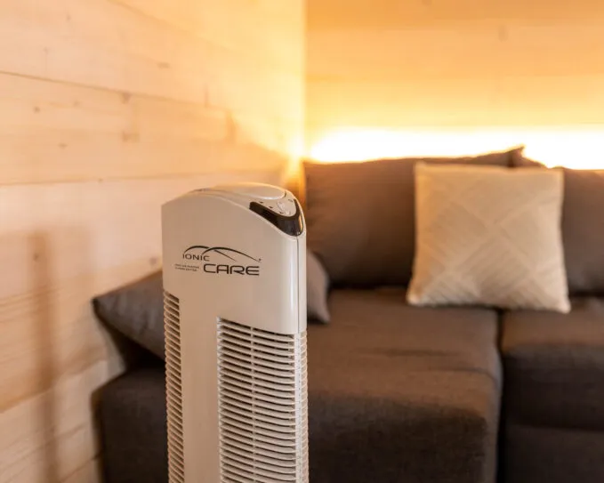 Čistička vzduchu Ionic-CARE v interiéru dřevostavby s pohovkou a osvětlením, barva perleťově bílá
