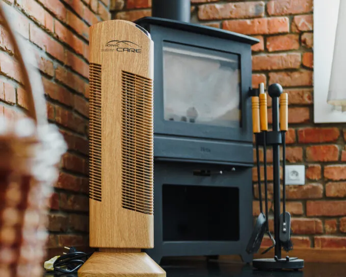 Čistička vzduchu Ionic-CARE v interiéru s cihlovým obložením a krbovými kamny, dekor dřevo dub