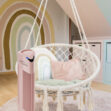 Růžová čistička vzduchu Ionic-CARE v dětském pokojíčku u houpacího křesla, v pozadí malba duhy