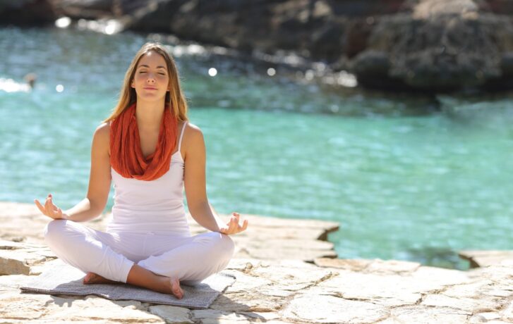 Jak správně dýchat při cvičení? Žena u vody v relaxační poloze se soustředí na správné dýchání