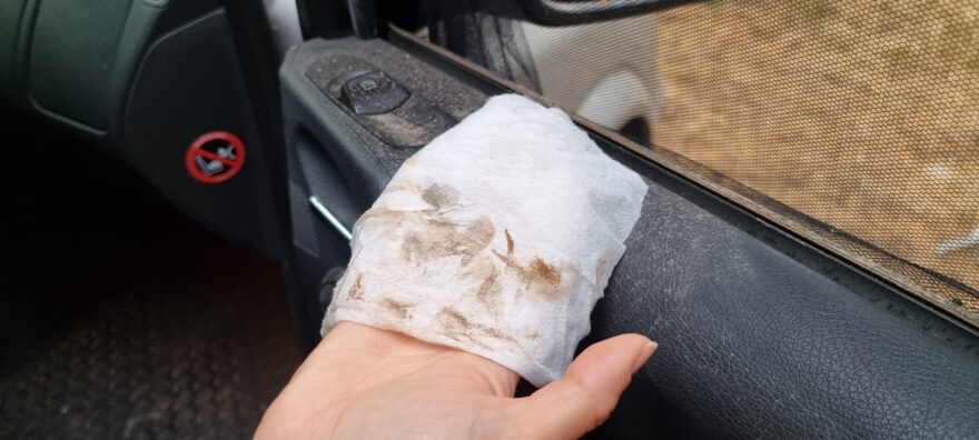 Špína ze saharského prachu na ubrousku v interiéru auta.