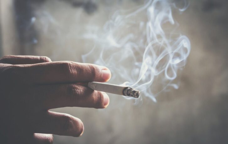 Zapálená kouřící cigareta v ruce.