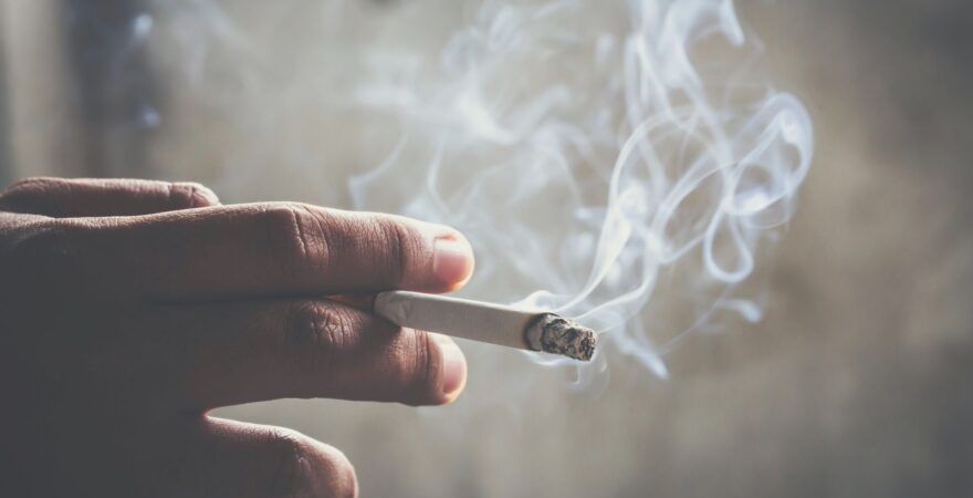 Zapálená kouřící cigareta v ruce.