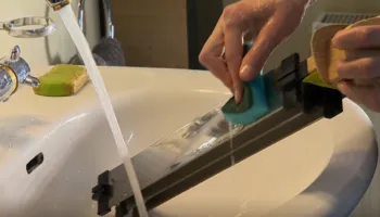 Mytí nerezového filtru čističky vzduchu Ionic-CARE pod tekoucí vodou v umyvadle